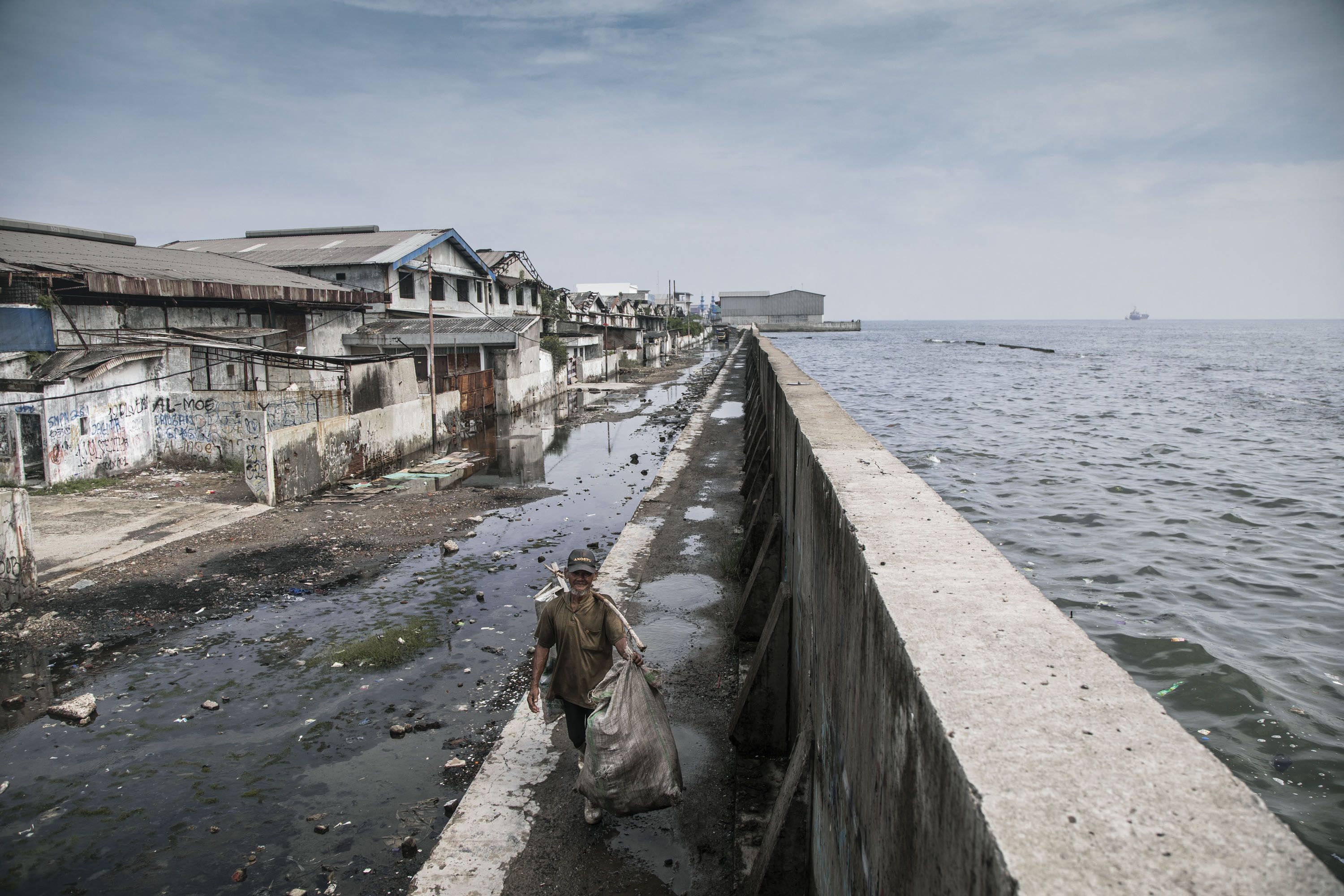 Man walking on top of a giant sea wall protecting Jakarta, Indonesia. Credit: Irene Barlian / Climate Visuals Countdown Man walking on top of a giant sea wall protecting Jakarta, Indonesia. Credit: Irene Barlian / Climate Visuals Countdown