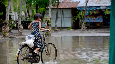 Burmese girl riding bicycle in flood area, Credits: Cities Alliance Burmese girl riding bicycle in flood area