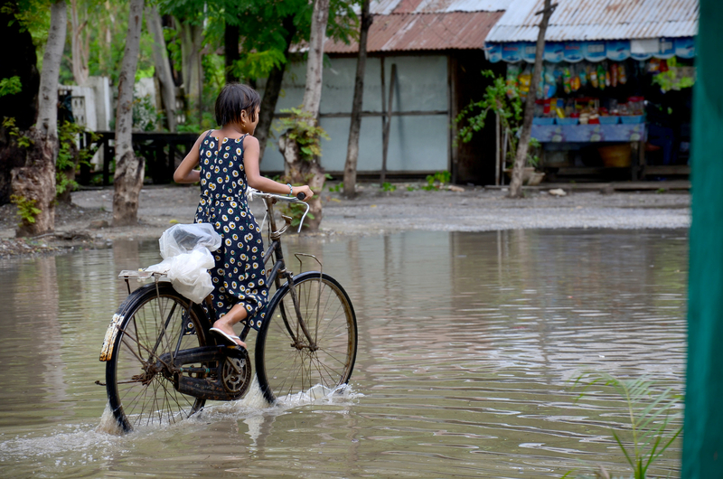 Burmese girl riding bicycle in flood area, Credits: Cities Alliance Burmese girl riding bicycle in flood area