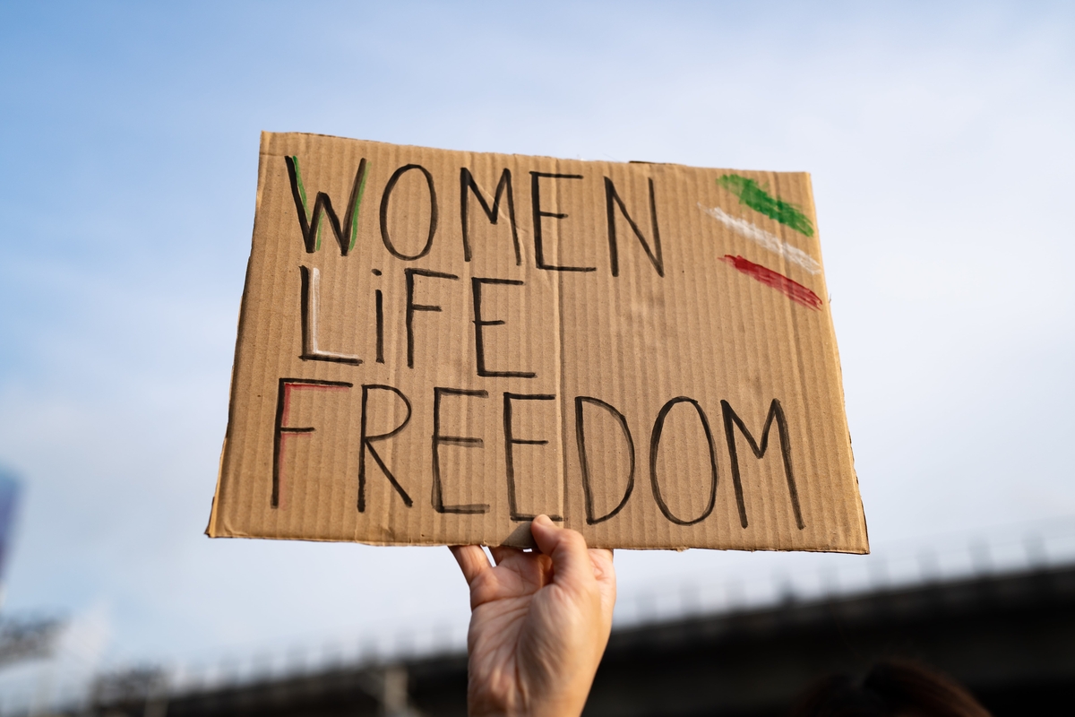Demonstrator holding 'Women, Life, Freedom' placard.  ©squirrel -​​​​​​ AdobeStock.com