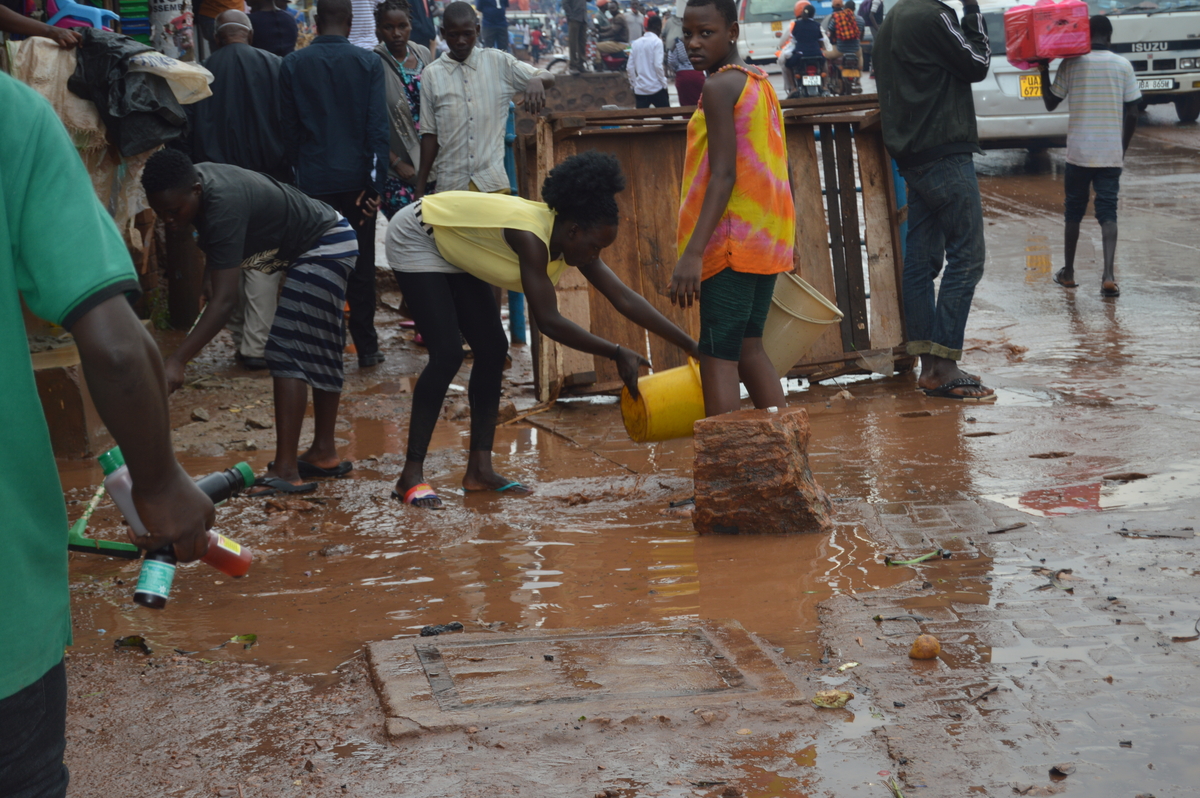 Bwaise residents cleaning up after a downpour. Photo Credit; TAU.JPG