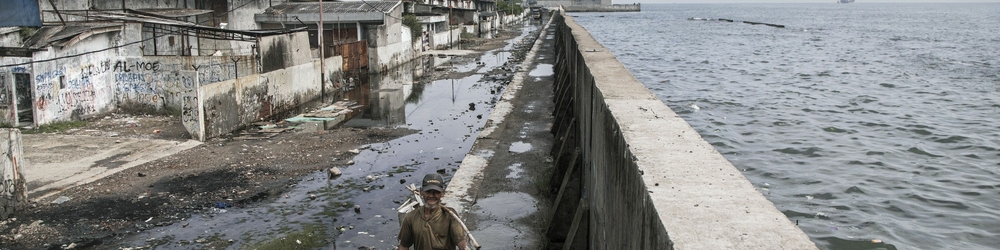 Man walking on top of a giant sea wall protecting Jakarta, Indonesia. Credit: Irene Barlian / Climate Visuals Countdown Man walking on top of a giant sea wall protecting Jakarta, Indonesia. Credit: Irene Barlian / Climate Visuals Countdown