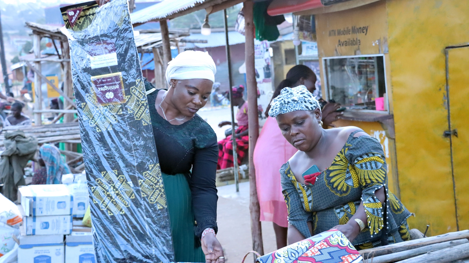 Solage Manamu (right) interacts with a customer at her kitenge stall in Koboko, Uganda. Photo: Bernards Okuyo